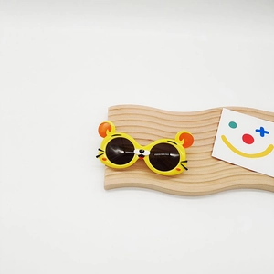 Gros plan de lunettes de soleil enfant en forme d'ours jaune sur présentoir en bois