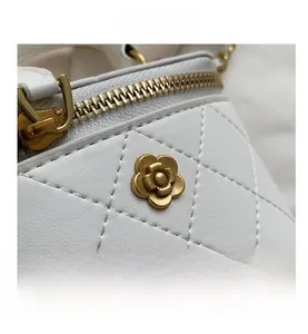 Macro detail of white quilted leather bag showing gold floral hardware and fine stitching