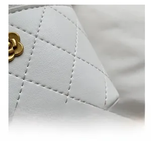 Detailed macro view of white quilted leather texture with gold camellia hardware detail