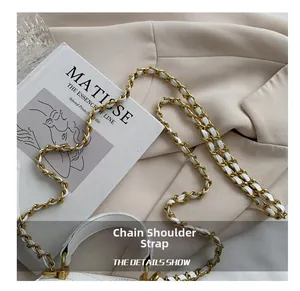 Detailed view of woven leather and gold chain strap on a white quilted mini box bag