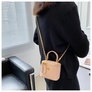 Detalle de mini bolso tipo cubo rosa acolchado con camelia dorada y cadena