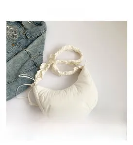 Close-up of a white quilted crossbody bag with gathered straps and drawstring detail