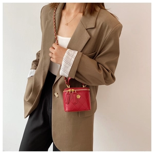Detalle del mini bolso acolchado rojo con cadena y cierre de flor dorada en modelo