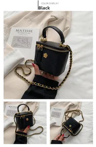 Detail of black quilted mini box bag with gold flower zipper and woven chain strap