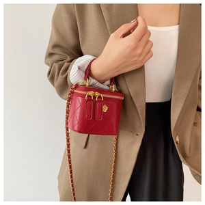 Detailed view of red quilted vanity case with gold floral ornament and chain strap