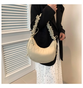 Detail view of beige crescent puffer bag with ruched strap and bow decorations
