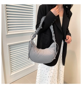 Detail of light gray puffy nylon crescent bag with ruched strap and side drawstring knots