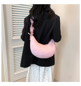 Detailed side view of pink quilted half-moon crossbody bag with ruffled shoulder strap