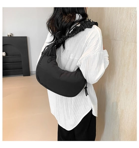 Side view of black crescent shoulder bag featuring stylish ruched strap detail