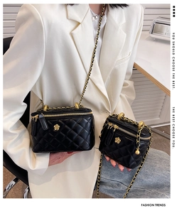 Close-up of black quilted leather bucket bags with gold camellia floral metal accents