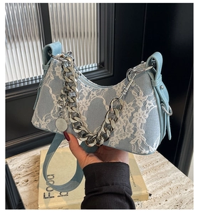 Detailed view of light blue lace fabric and silver metal chain strap on underarm bag