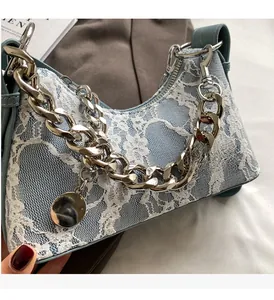 Close-up of light blue lace shoulder bag with silver chain strap and metal charm