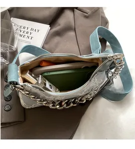 Interior view showing the spacious compartment and silver chain of this light blue denim bag