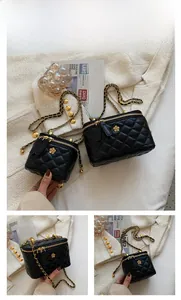 Close-up of black quilted chain vanity bags in two sizes with gold floral ornaments