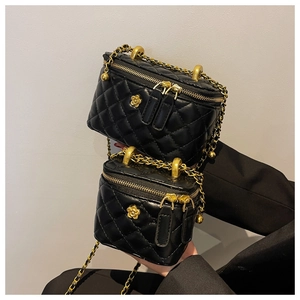 Detail of black quilted bucket bags featuring golden chain straps and camellia accents