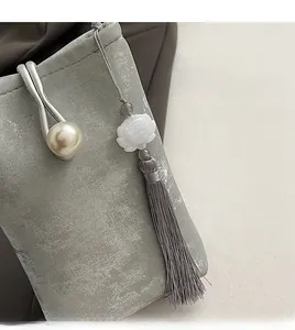 Gros plan sur la boucle en perle et le pompon lotus d'un sac texturé gris élégant
