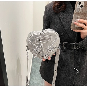 Détail du sac à bandoulière argenté en forme de cœur avec rivets et fermetures à franges