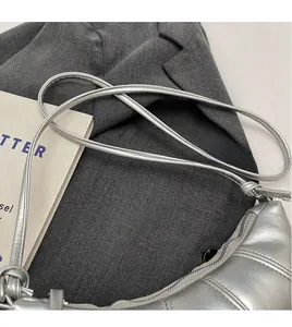 Detail of silver quilted half-moon bag featuring unique knotted strap and metallic texture