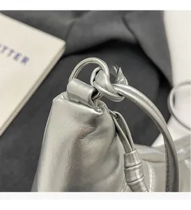 Detail of silver metallic shoulder bag with lychee texture and knotted strap design