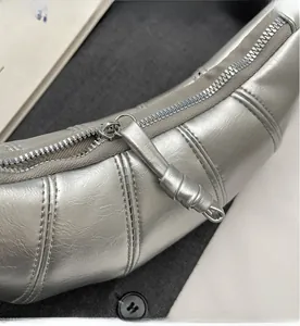Detailed close-up of the smooth metal zipper and silver PU leather on croissant bag