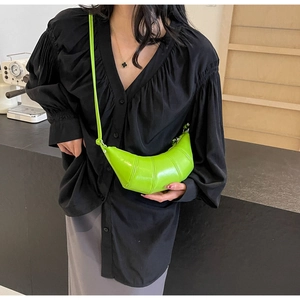 Model wearing a neon green croissant crossbody bag with vertical quilted stitching detail