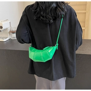 Close-up of vibrant green croissant crossbody bag with signature pleated leather detail