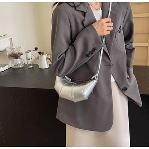 Detail view of a silver metallic croissant bag with segment stitching shown as a crossbody