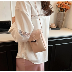 Elegant apricot mini crossbody phone bag with horn toggle closure shown on model detail.