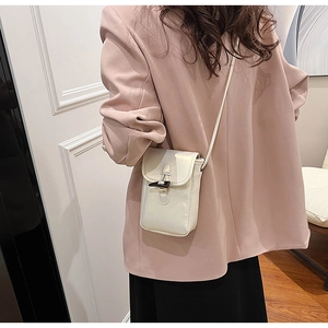 Back view of a fashionable white mini crossbody cell phone bag worn over a pink blazer.