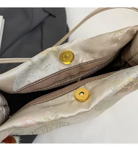 Dettaglio della chiusura magnetica dorata e ricamo su borsa a secchiello in seta