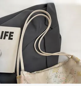 Dettaglio del ricamo floreale su una borsa a secchiello vintage con tracolle sottili