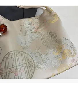 Dettaglio del tessuto satinato jacquard color oro champagne con ricami floreali cinesi
