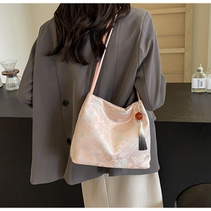 Dettaglio della borsa a secchiello rosa ricamata con jacquard cinese e ciondolo nappa