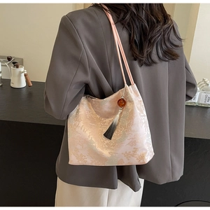 Dettaglio del ricamo in stile cinese su una borsa a secchiello beige con nappina