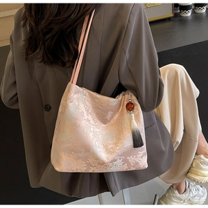 Dettaglio del ricamo jacquard rosa e del ciondolo con nappa su una borsa a secchiello