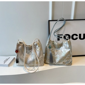 Dettaglio della borsa a secchiello in jacquard ricamato con motivi paesaggistici e nappe