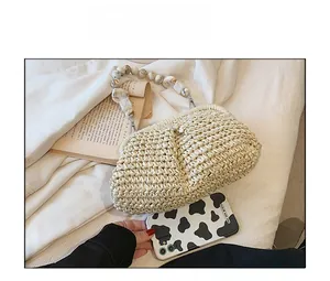 Detail of woven straw bag with marble resin bead handle next to a phone case for scale