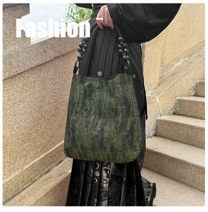 Detail of moss green tote bag featuring unique beaded handle and artistic brush texture