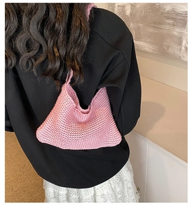 Detailed knit texture of pink handmade shoulder bag worn by model in casual setting