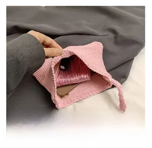 Macro view of pink knitted shoulder bag interior showing daily essentials like phone and wallet