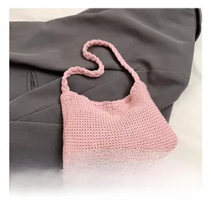 Close-up of pink knit handbag with thick woven texture on a grey fabric backdrop