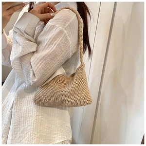 Detail of a handmade beige crochet shoulder bag showing thick knitted texture and strap