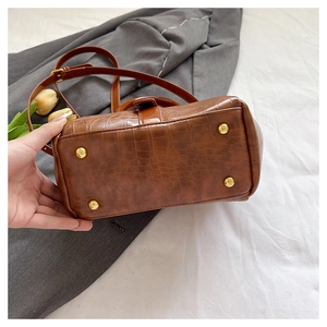 Nahaufnahme des braunen Krokodilmuster Vintage Handtaschenbodens mit vier goldenen Metallfüßen.
