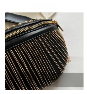 Detail of black leather dumpling bag featuring gold bead tassels and metallic hardware