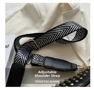 Detail of adjustable black and white woven shoulder strap with gold metal hardware
