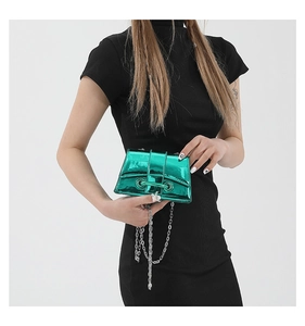 Gros plan sur le mini sac bandoulière vert métallisé avec chaîne argentée sur robe noire