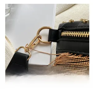 Detail of premium gold-toned hardware hooks and ball chain on a black leather crossbody bag