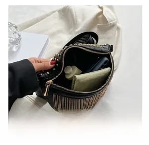Detail show of black quilted crossbody bag with gold studs, fringe, and internal capacity