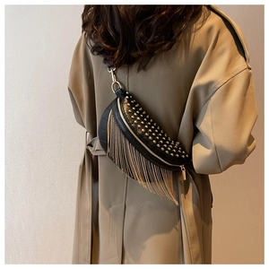 Detailed view of punk style black leather saddle bag with golden studs and long tassels