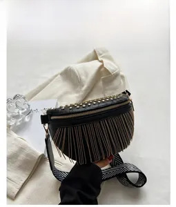 Detail of black crossbody bag featuring gold tassels, studs and a woven strap